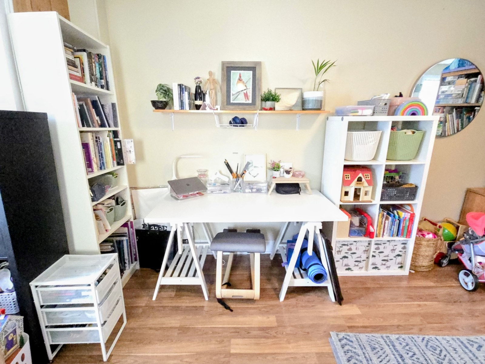 Closer view of the same shelving unit, with woven baskets, a dollhouse, and books sorted into individual cubbies.