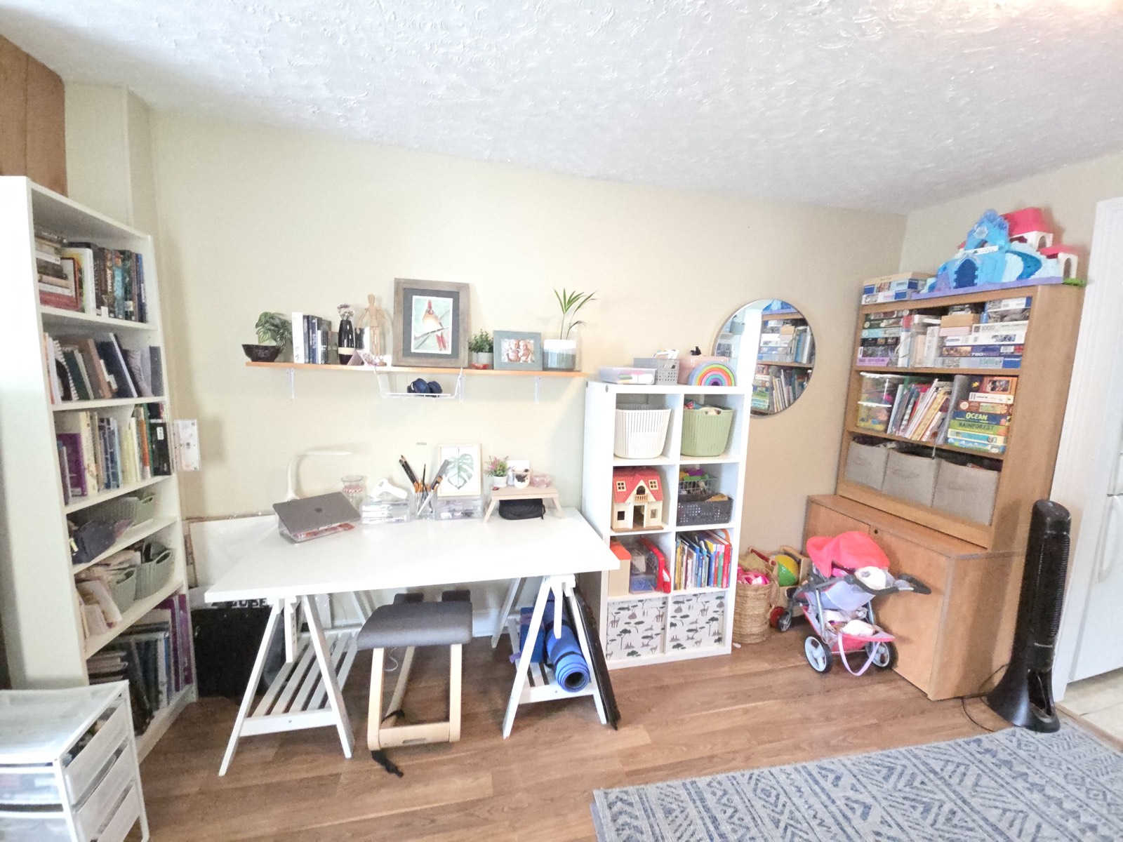 Home office and craft nook with a clutter-free desk, labeled bins, and toys and books sorted into open shelving cubbies.