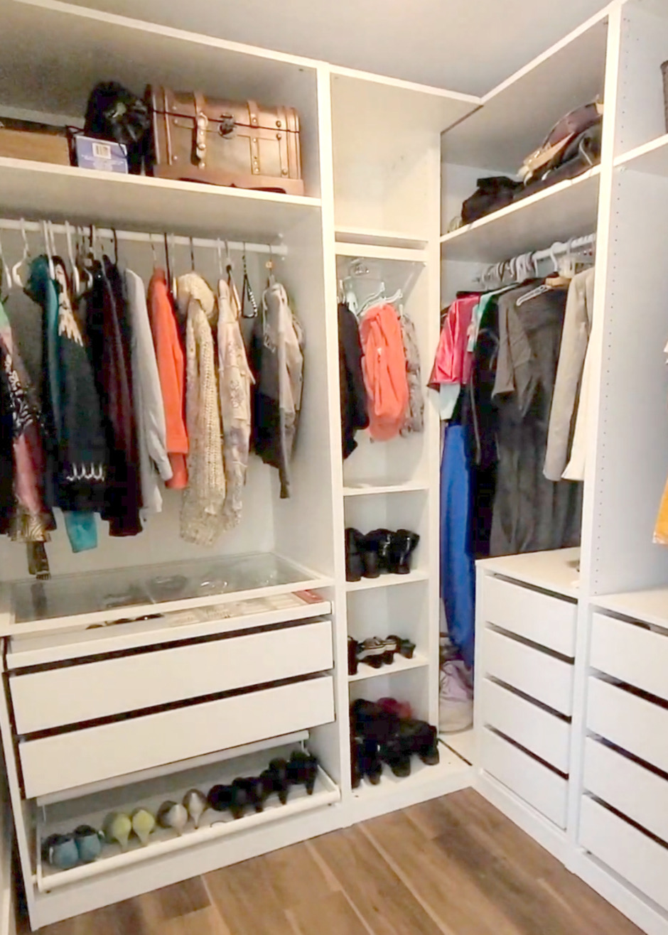 Open wardrobe closet with clothes hung neatly on one side, glass-front drawers below, and a labeled shoe cubby on the other side.